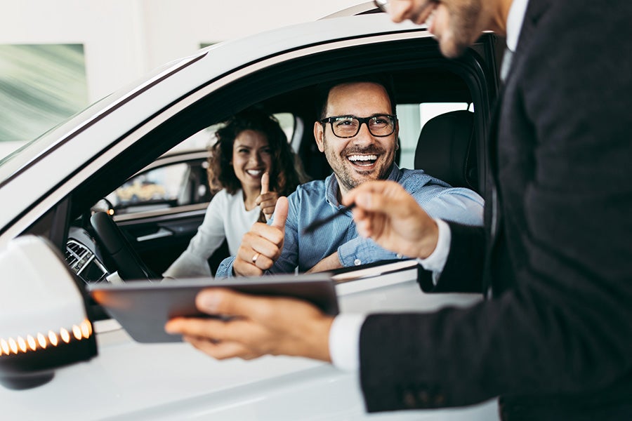 Couple Sitting in a Car Talking to a Representative